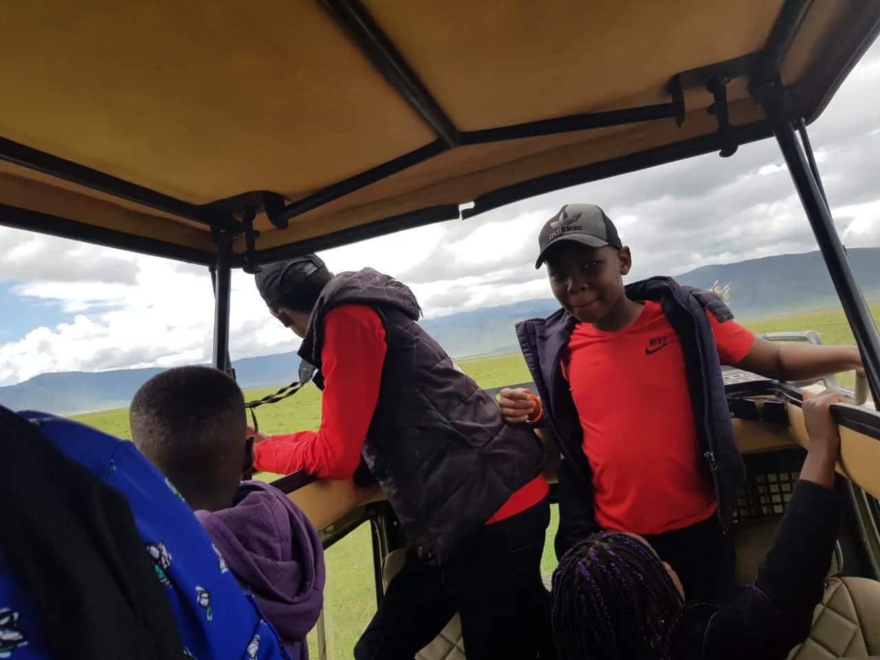 Young travellers standing up through the roof hatch on a game drive.