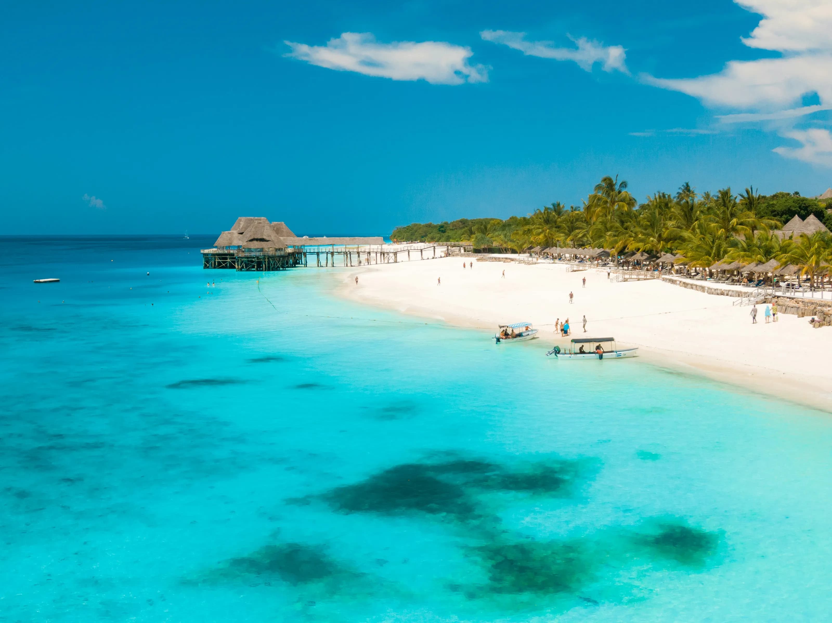 A thatched jetty reaching over the turquoise shallows of a Zanzibar bay.