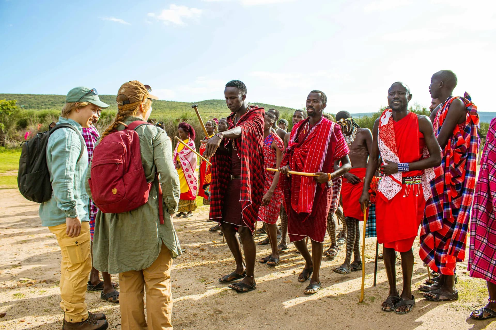 Travellers being greeted by a group of Maasai men and women.